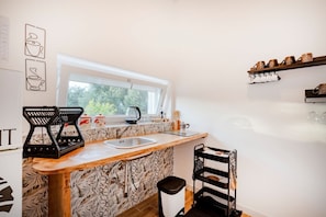 Une cuisine compacte avec une fenêtre, un évier, une bouilloire et une machine à café.