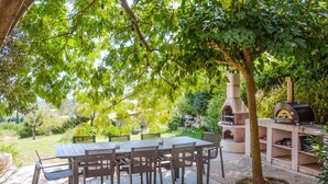 An outdoor patio with a table and chairs, surrounded by lush greenery and a stone wall. - Cozy home in Rochefort du gard (Rochefort du gard)