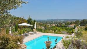 A swimming pool with a view of a town and hills in the background. - Cozy home in Rochefort du gard (Rochefort du gard)