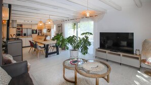 A modern living room with a large TV, two glass coffee tables, a sofa, and a dining area with a kitchen in the background. - Cozy home in Rochefort du gard (Rochefort du gard)