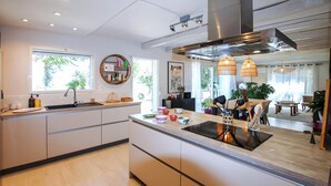 A modern kitchen with a central island, built-in appliances, and a dining area with a view. - Cozy home in Rochefort du gard (Rochefort du gard)