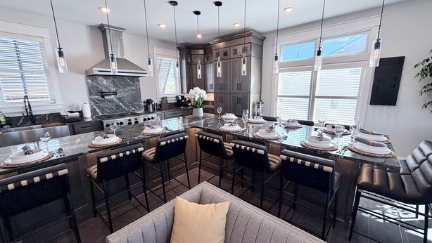 Una cocina moderna con una isla central, muebles oscuros e iluminación colgante.