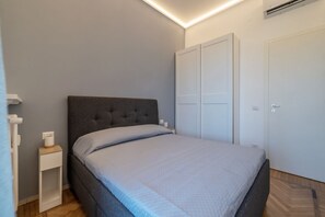 Une chambre à coucher avec un lit, une table de chevet, une armoire et une porte.