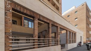 A building with a brick facade, a covered parking area, and a clear sky. - GuestHost - Comfortable apartment located on the seventh floor, of nine in total, equipped with a lift (NOT suitable for disabled people). There are steps at the entrance.In 65 m2 of space it accommodates 2 people with a double bedroom.The location is ex (Roma)