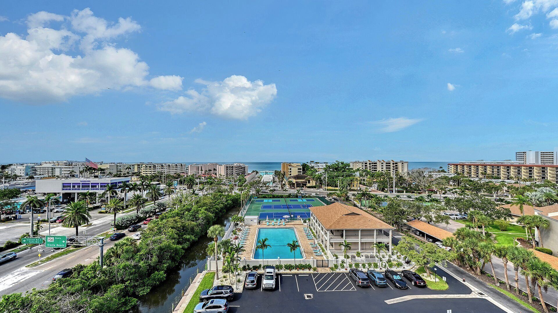 A resort with a swimming pool, tennis courts, and a view of the ocean.