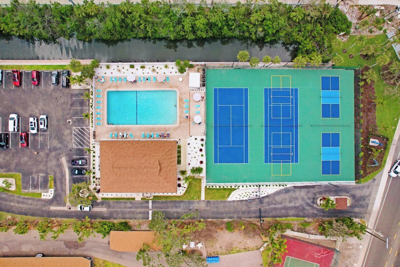 Vista aerea di un resort con piscina, campi da tennis e un’area parcheggio.