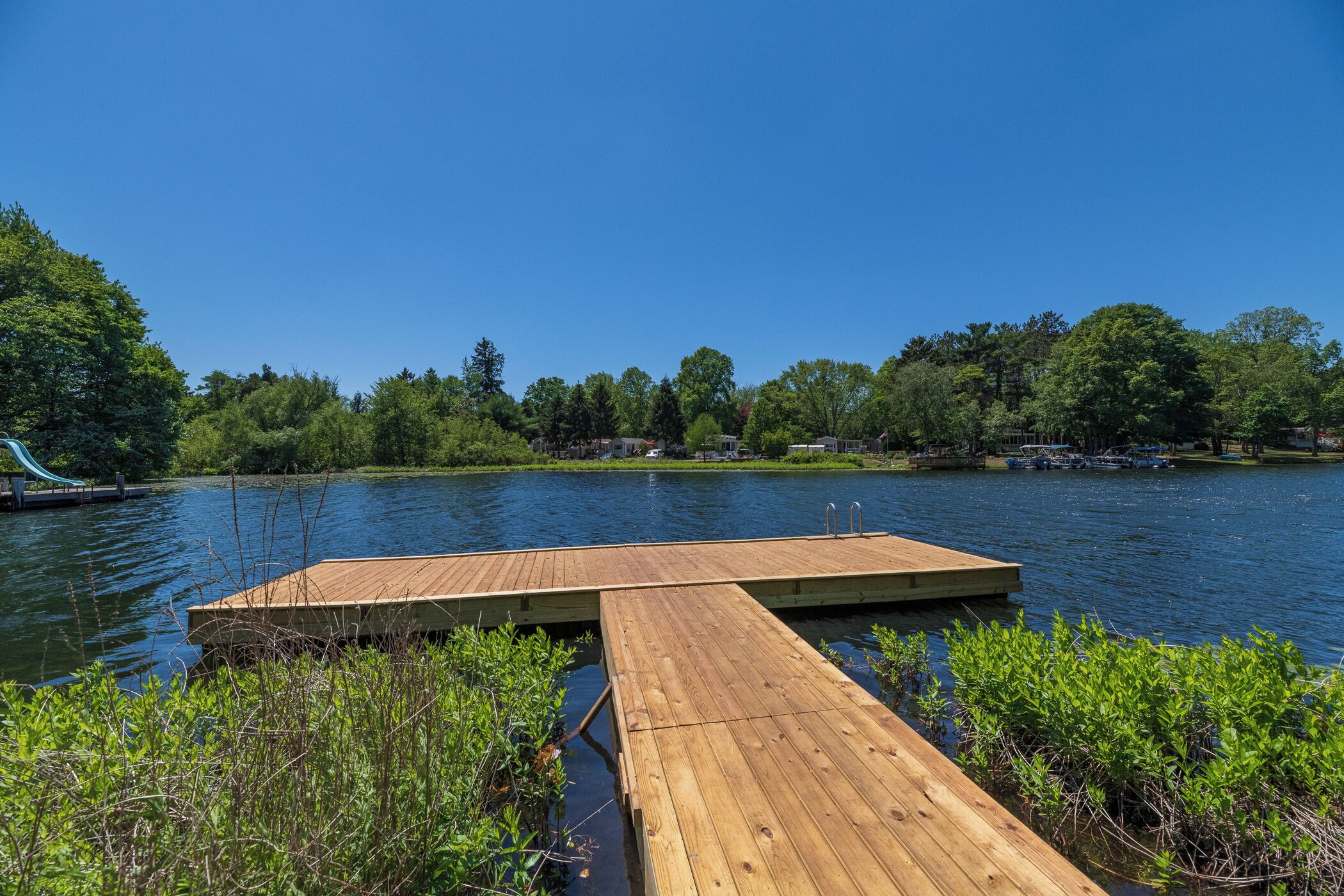 A wooden dock extending into a lake with a clear blue sky above.