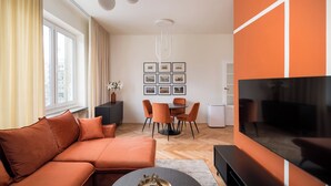 A modern living room with a sectional sofa, a coffee table, a TV, and a dining area with a table and chairs. - Warsaw Dream Apartment (Warszawa)