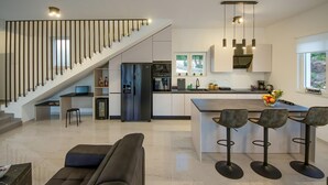 A modern kitchen with a central island, bar stools, and a staircase leading to a lofted area. - Pet friendly home in Sibenik (Sibenik)