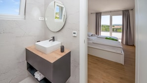 A modern bathroom with a white sink, a mirror, and a wooden vanity. - Pet friendly home in Sibenik (Sibenik)