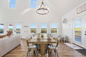 A spacious dining area with a long wooden table, metal chairs, and a chandelier.