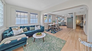 Un salón amplio con un sofá azul, un comedor y una cocina al fondo.