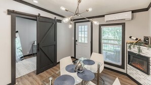 A modern living room with a glass dining table, a fireplace, and a sliding barn door. - Modern Casita w/Outdoor Tub- Unit B (Madison)