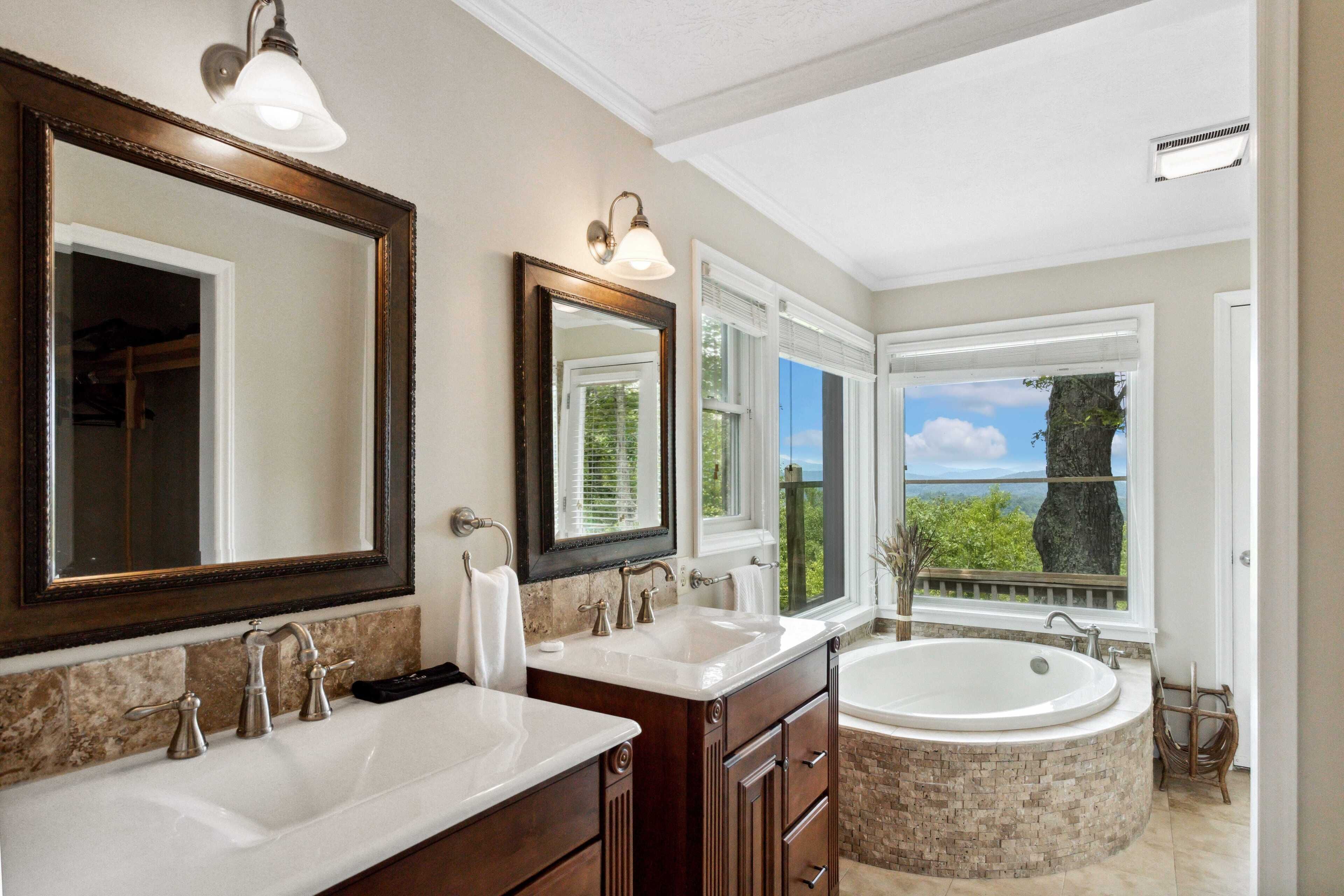 A bathroom with two sinks, a large bathtub, and multiple mirrors.