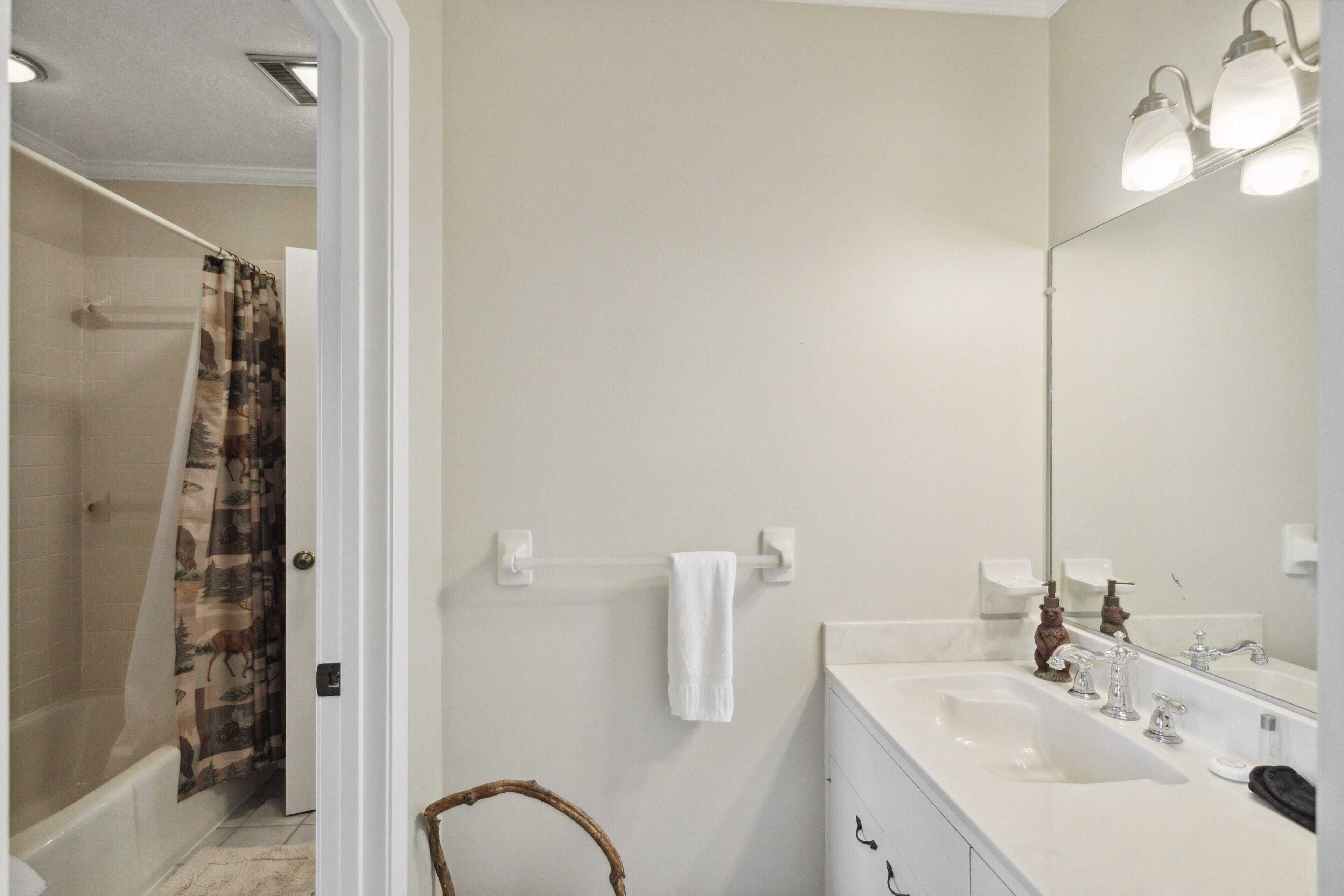 A bathroom with a white sink, mirror, and towel rack.