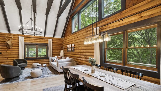 Ein rustikales Holzhäuschen-Interieur mit Essbereich, Sofas und einer Pendelleuchte.