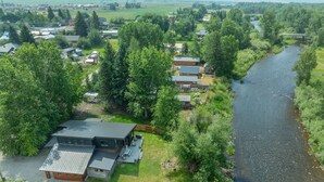 A riverside property with a large house, a smaller cabin, and a boat dock. - Gallatin River Retreat: 3BR Home with Hot Tub, Fly Fishing & Stunning Views (Gallatin Gateway)