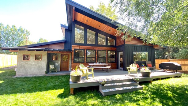 A modern house with a patio, outdoor seating, and a barbecue area. - Gallatin River Retreat: 3BR Home with Hot Tub, Fly Fishing & Stunning Views (Gallatin Gateway)