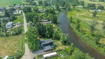 An aerial view of a rural area with a river, houses, and a small bridge.
