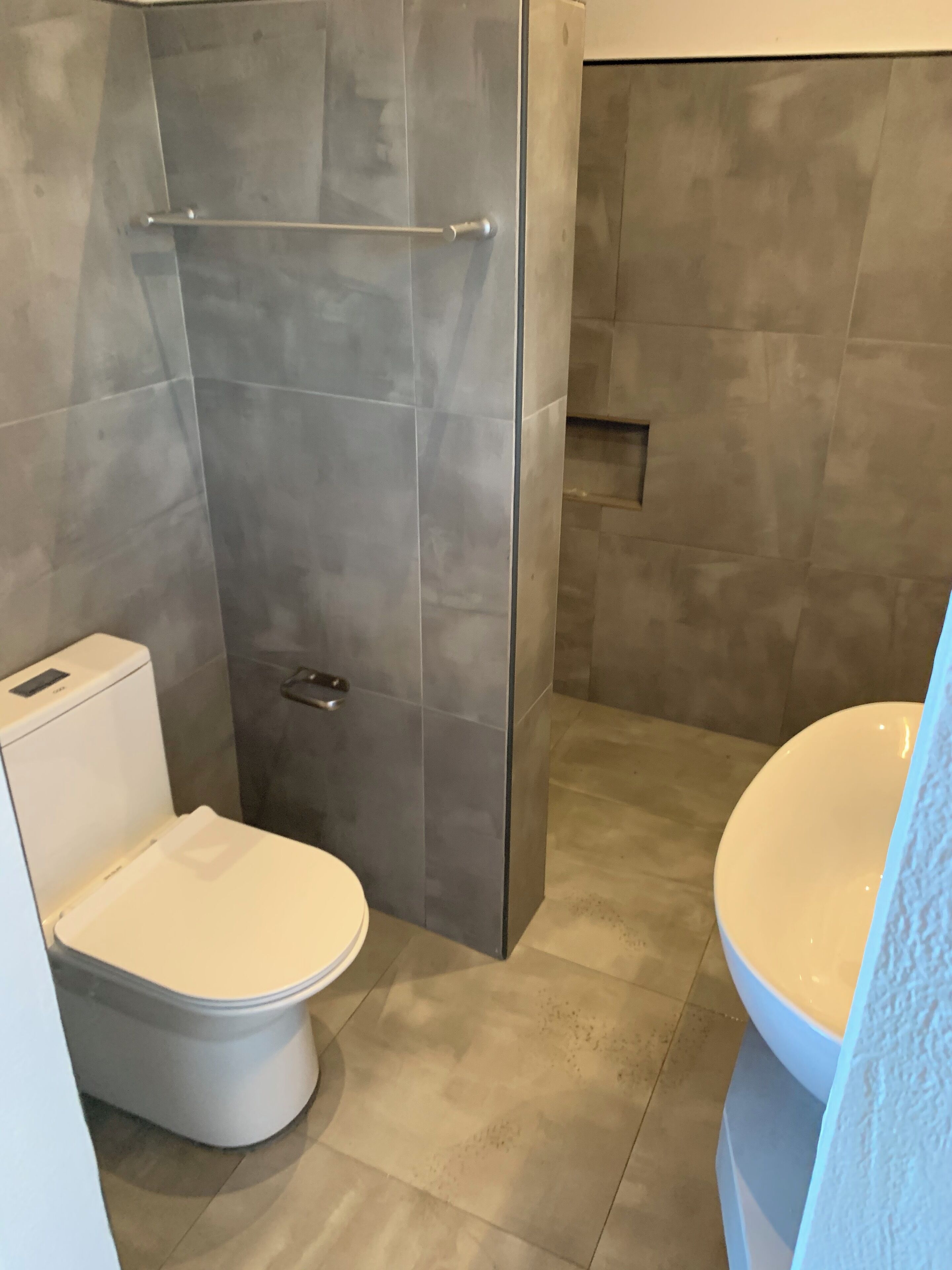 A modern bathroom with a glass-enclosed shower, a toilet, and a sink.