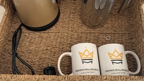 A tray with a coffee maker, a pot, and two mugs with a hotel logo. - Crown Malapascua (Daanbantayan)