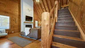 A wooden interior with a staircase, a fireplace, and a sofa. - HazelBrook Haven- Hot Tub, Firepit, Grill (Hazel Green)