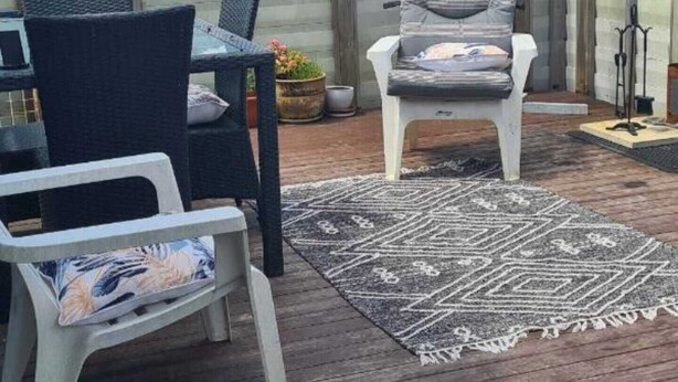 A deck with outdoor furniture, a pergola, and a view of a house in the background. - Westgate Three and one small room house 🏠  (Auckland)