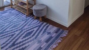 A room with a wooden bench, a small stool, a patterned rug, and a framed picture on the wall. - Westgate Three and one small room house 🏠  (Auckland)