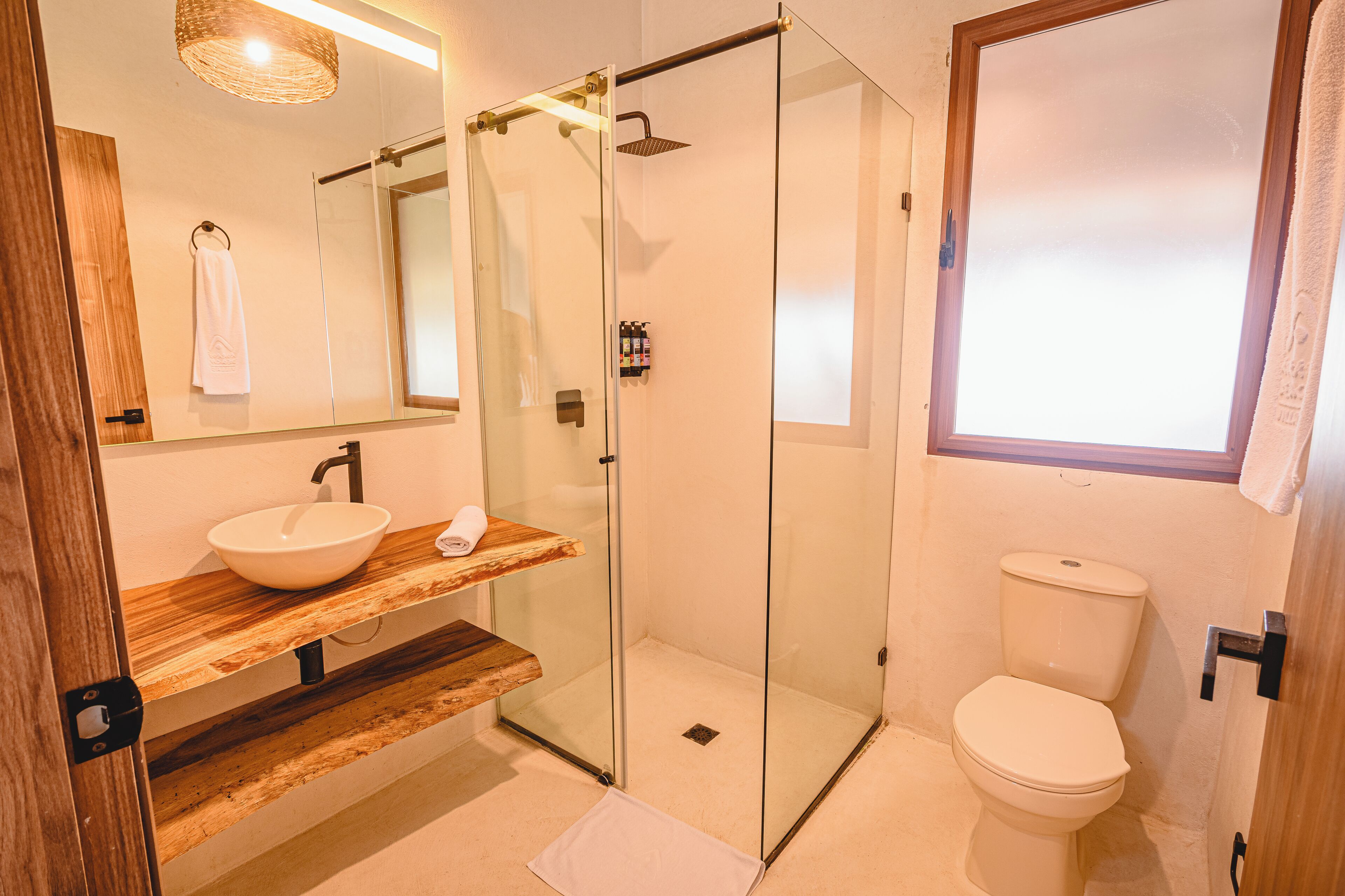 Un bagno moderno con doccia a vetro, mobile bagno in legno e water bianco.