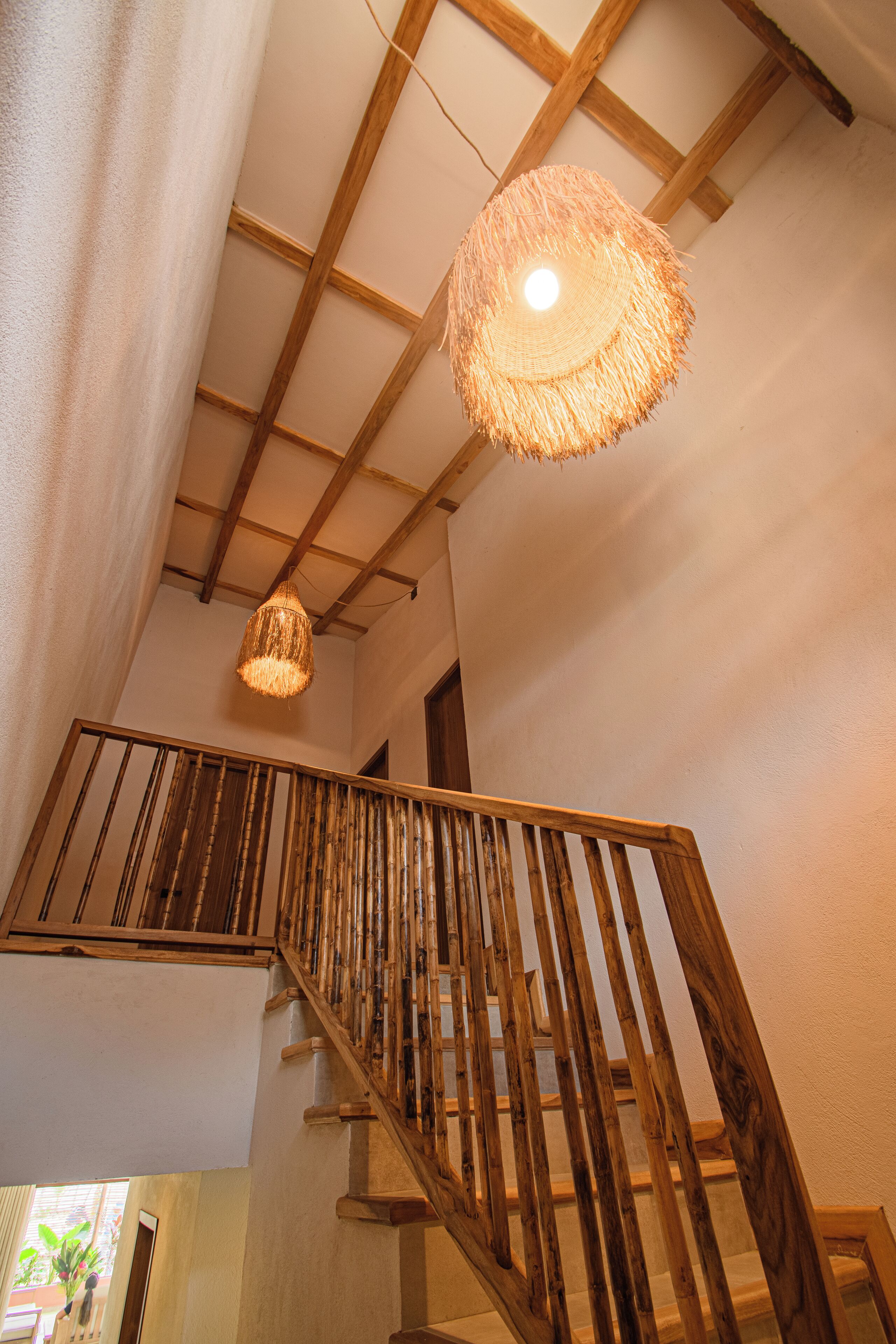 Eine Holztreppe mit einer gewobenen Leuchte darüber.