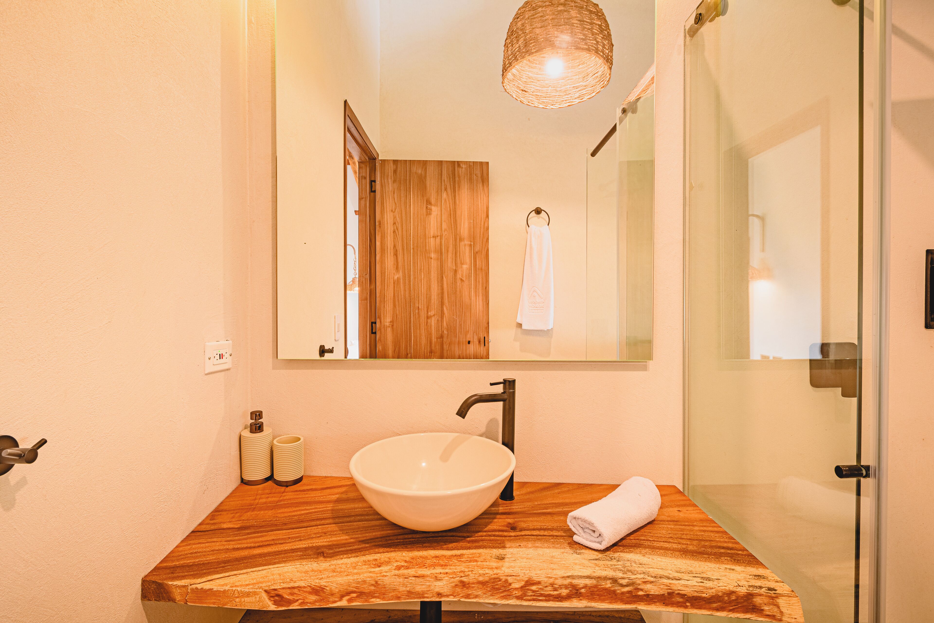 A bathroom with a wooden vanity, a white sink, and a mirror above it.