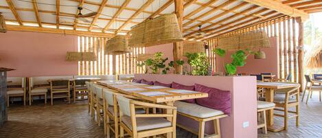 A restaurant with wooden tables and benches, a herringbone floor, and a bamboo ceiling.