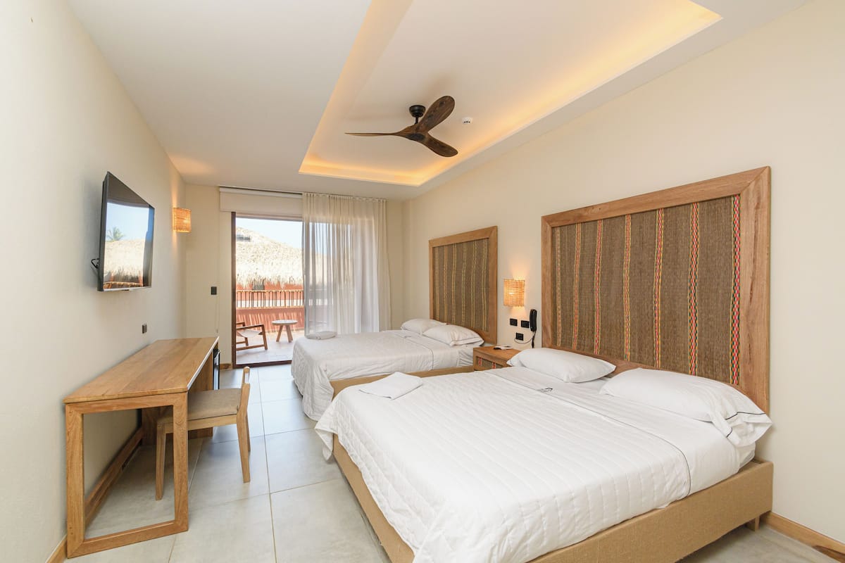 Une chambre d’hôtel avec deux lits, un bureau et un ventilateur de plafond.