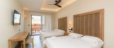 A hotel room with two beds, a desk, and a ceiling fan.