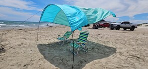 A beach with a blue canopy and striped beach chairs. - NEWLY RENOVATED - 2/2 Condo - A Short Walk to the Beach - Sleeps 6 Comfortably (Corpus Christi)