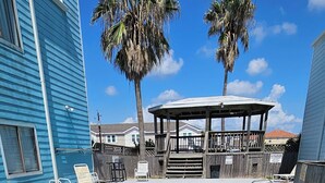 Une piscine avec des chaises longues, une terrasse en bois et des palmiers.