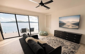 Uma sala de estar moderna com uma janela grande, um sofá, uma televisão e um ventilador de teto.