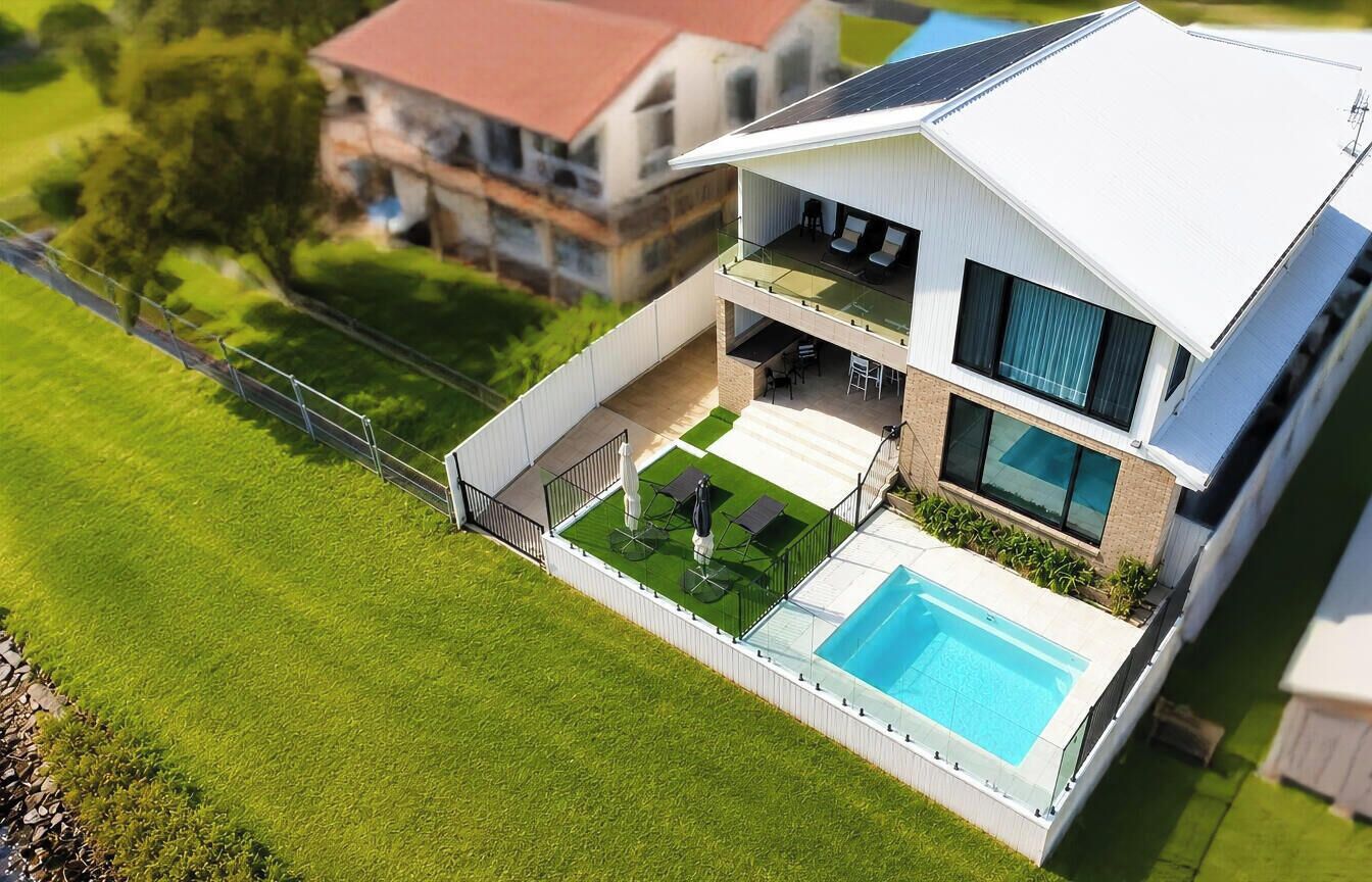 Ein modernes, zweistöckiges Haus mit Swimmingpool, Balkon und umzäunter Garten.