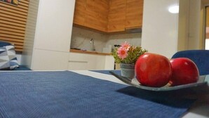 A room with a bed, a small table with apples and a flower, and wooden cabinets.