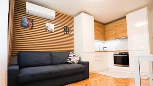 A modern kitchen with wooden cabinets, a built-in oven, and a herringbone-patterned floor.