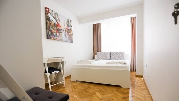 A compact bedroom with a bed, a small desk, and a chair.