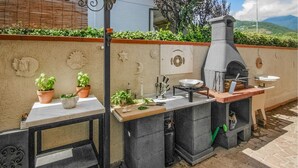 An outdoor kitchen with a stone oven, a marble countertop, and potted herbs.
