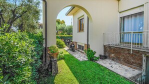 A residential property with a paved driveway, a small lawn, and a brick wall.