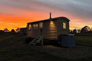 A wooden cabin with a chimney, a set of stairs, and a small outdoor area.
