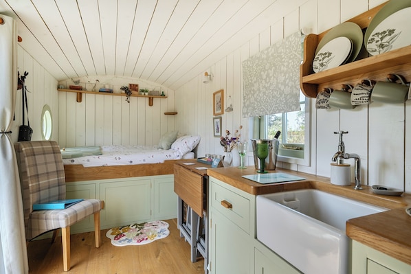 A compact kitchen with wooden cabinets, a sink, and a window.
