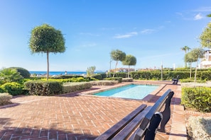 A pool area with a brick pathway, benches, and neatly trimmed hedges. - Sunset Golf Gold, Estepona, Spain (Estepona)