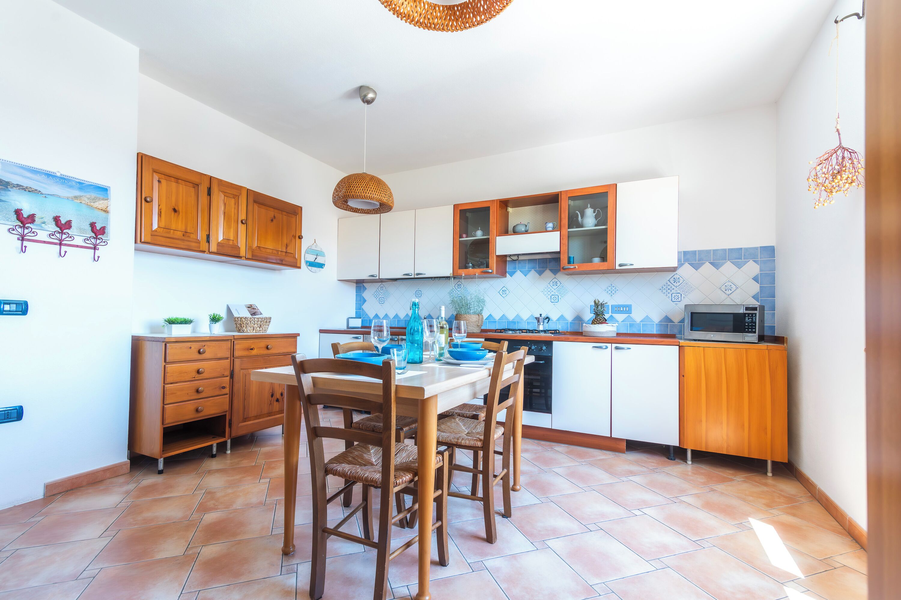 A kitchen with wooden cabinets, a dining table with chairs, and a microwave.