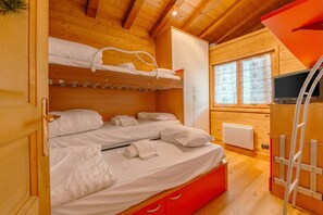 A wooden cabin room with bunk beds, a TV, and a window with decorative glass.