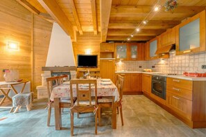 A wooden cabin interior with a dining area, kitchen, and a television.