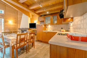 Een houten interieur met een eethoek, keuken en een televisie.